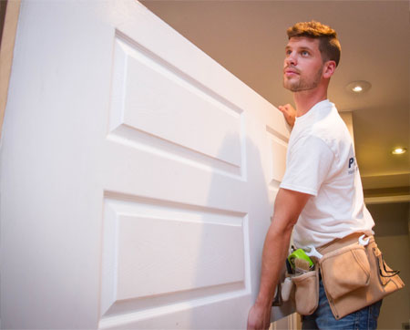 Prep'n Sell's professional handyman carefully inspects a white door for quality and durability in a home setting.
