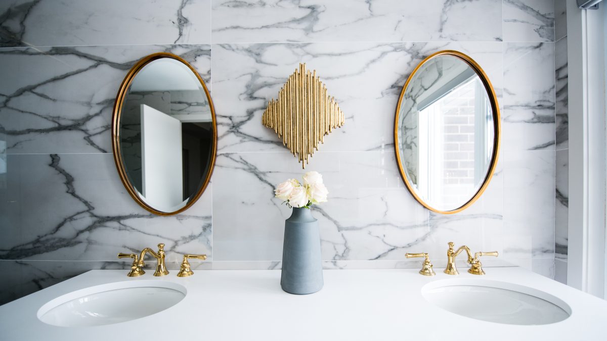 Chic bathroom vanity with marble backdrop, dual round mirrors, and gold accents.