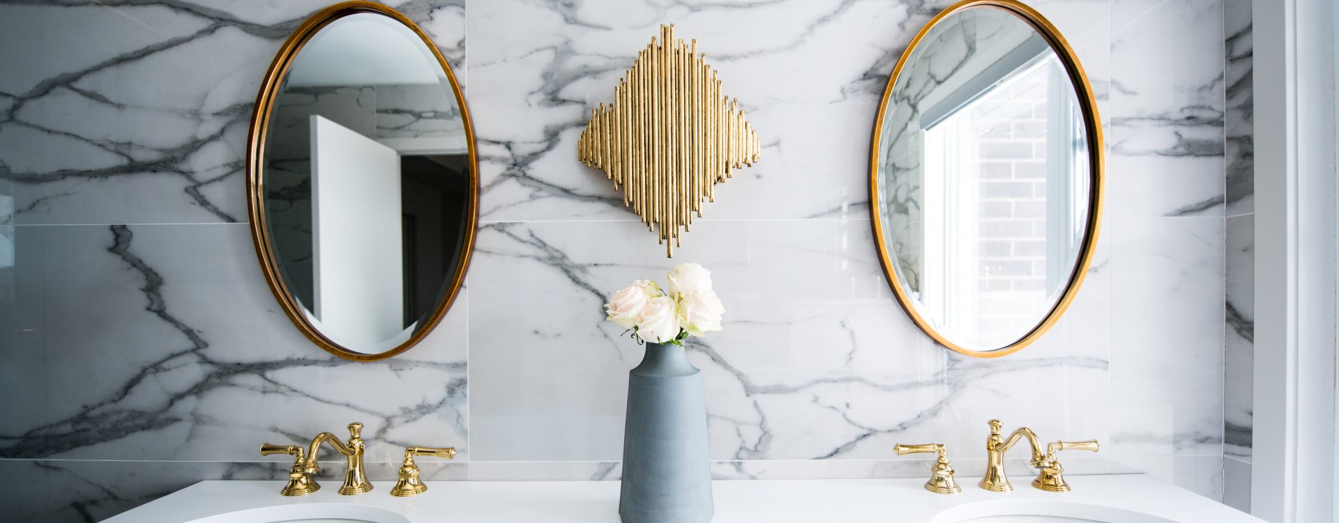 Chic bathroom vanity with marble backdrop, dual round mirrors, and gold accents.