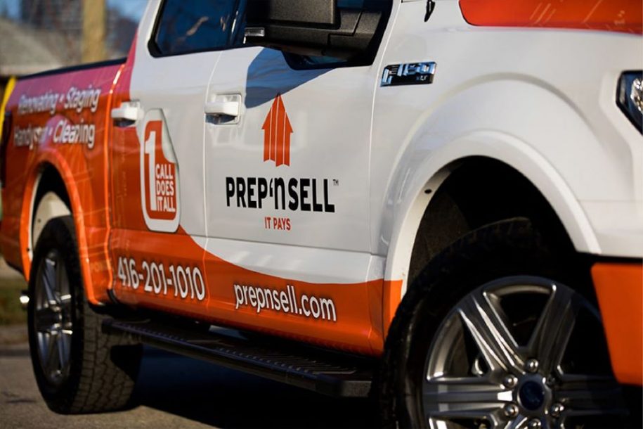 A side view of a Prep'n Sell branded white and orange pickup truck.
