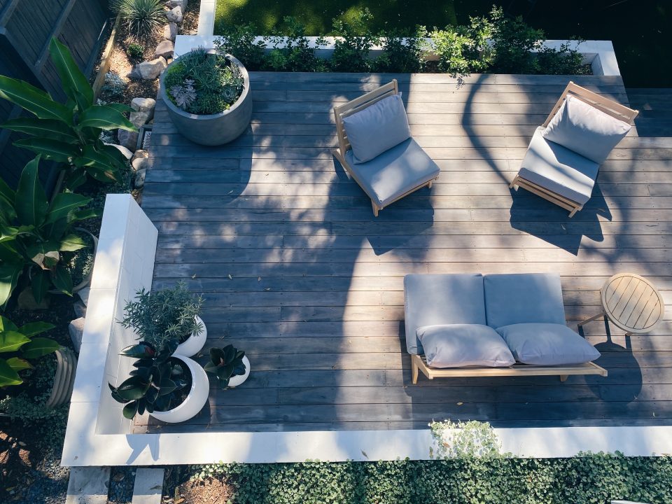 Aerial view of a modern backyard patio with wooden decking and cozy furniture.