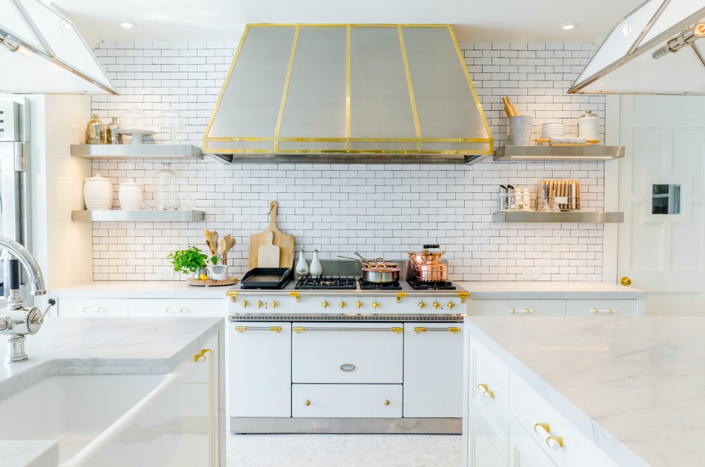 A pristine modern kitchen with white cabinetry and gold accents, a result of Prep'n Sell's high-end finishing touches.