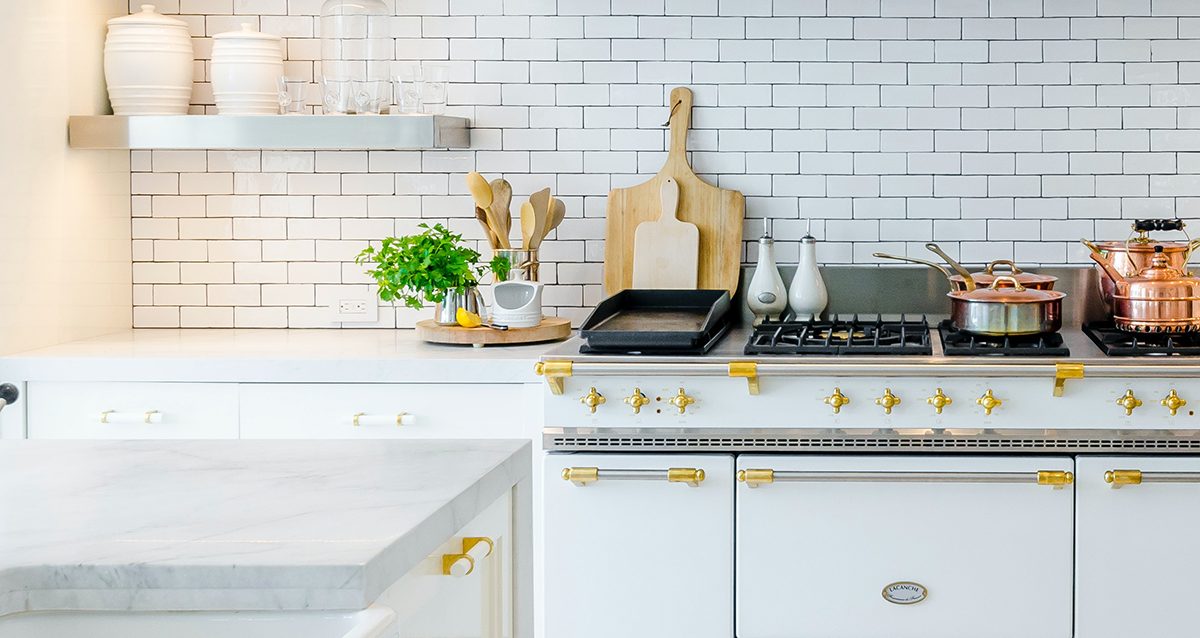 Sleek kitchen showcasing white marble countertops and a classic stove with brass accents.