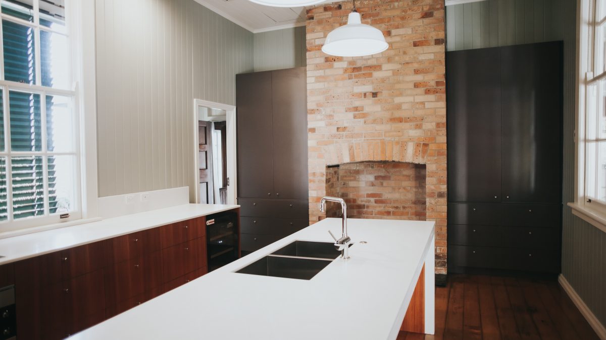 Spacious kitchen with white island countertop and exposed brick walls.