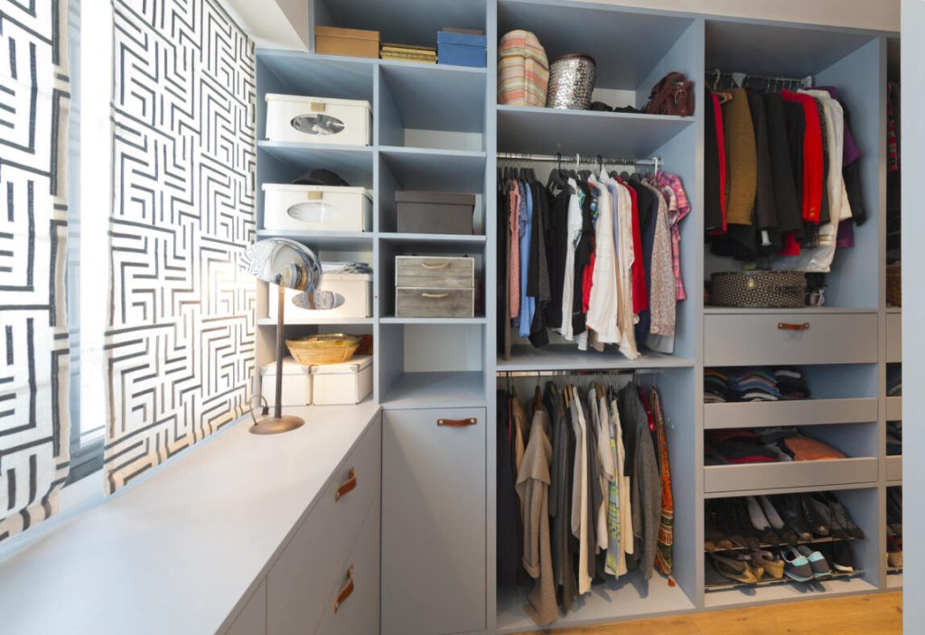 Clean and organized closet with neatly arranged clothes and shoes.