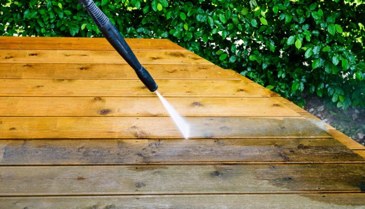 Person power washing a wooden deck to refresh it for spring.